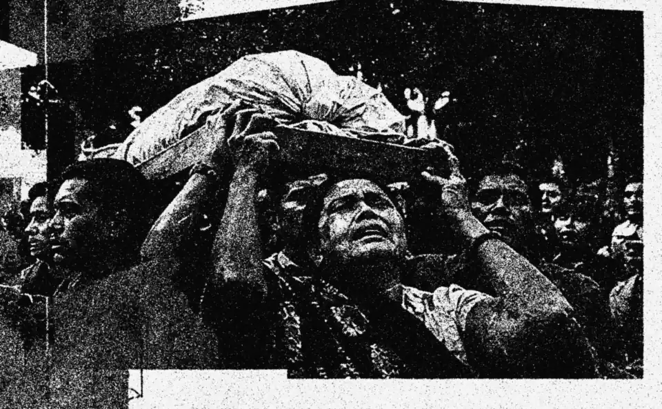 Mourners carrying a body through a crowd