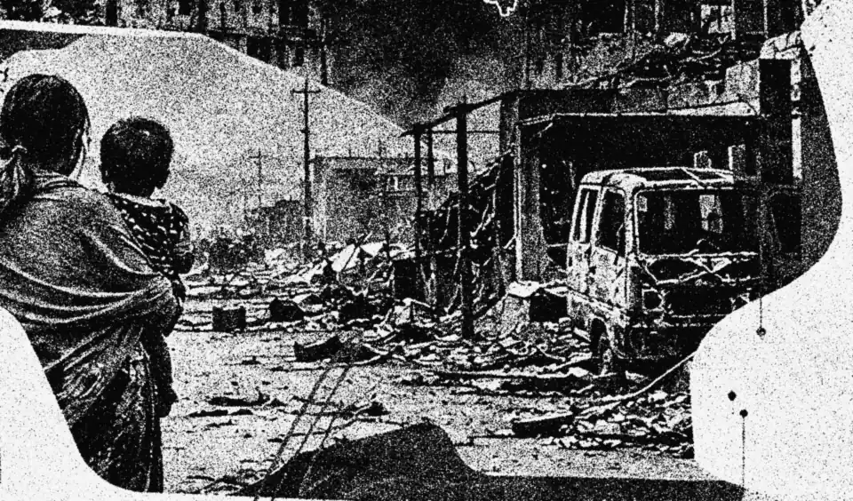 A mother carries her child through a burnt-out street