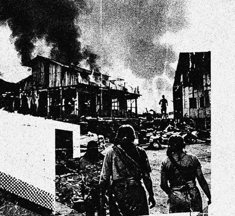 Women walking away from a burning village