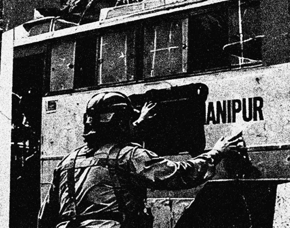 A state bus with the word Manipur covered, guarded by security forces